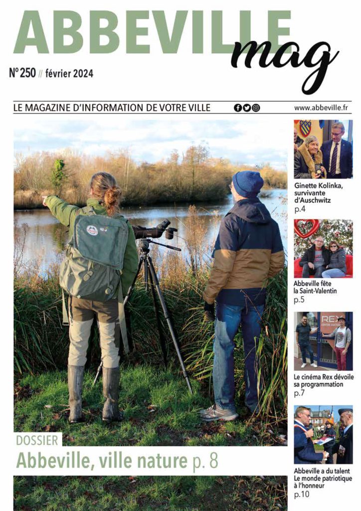 Un photographe naturaliste et son compagnon, munis de sacs à dos, se tiennent au bord d'une rivière, pointant un appareil photo sur un trépied vers les oiseaux. La couverture du magazine présente des articles sur Ginette Kolinka, la Saint-Valentin, la nature d'Abbeville et le cinéma Rex.